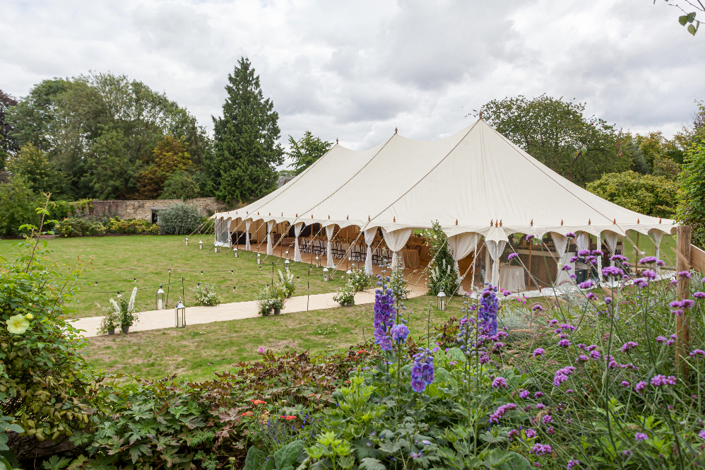 Luxury garden wedding at home with beautiful white canvas marquee surrounded by trees and flowers in the English countryside