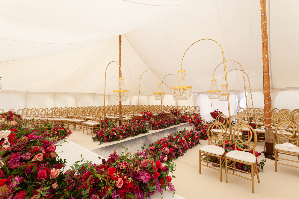 Luxury outdoor wedding ceremony for 200 guests in a huge white canvas marquee decorated with luxe red and pink florals and statement chandeliers