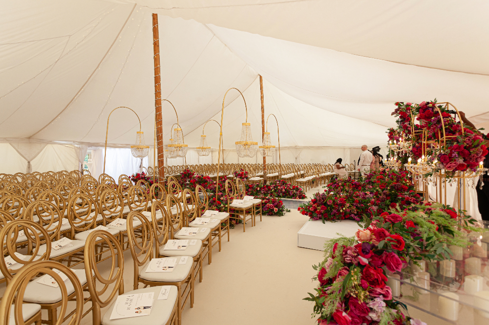 Luxury marquee wedding ceremony set up for 300 guests with luxe chairs, huge statement florals in red and pink and dramatic chandeliers